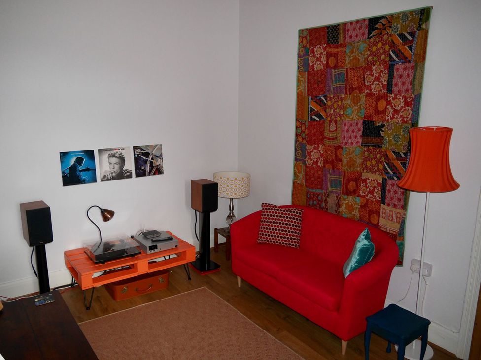 A living room with a red sofa and a record player at Anchor Cottage in Cleethorpes