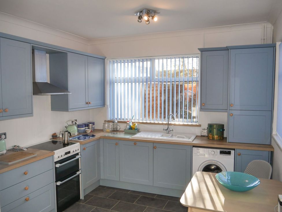 A kitchen with cabinets, oven, sink, and washing machine at Anchor Cottage Cleethorpes