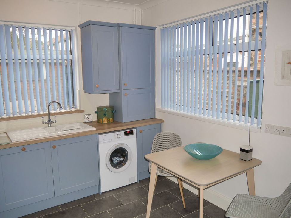 A kitchen with a sink, washing machine, and table at Anchor Cottage in Cleethorpes