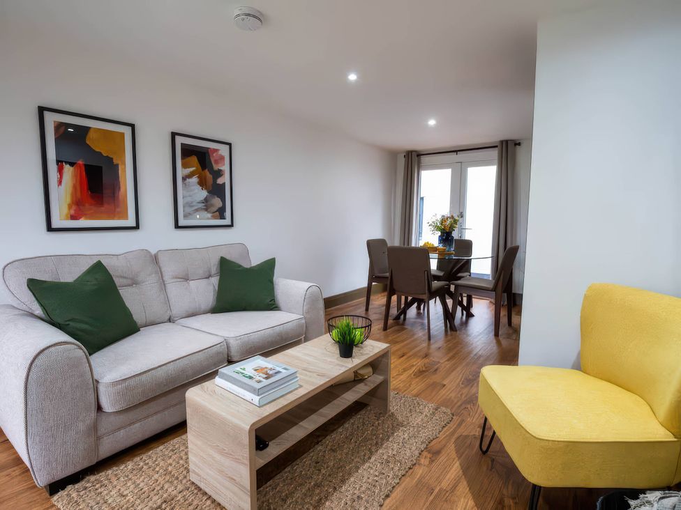 A living room with a sofa a coffee table and a dining area at Beech Cottages Llanrwst