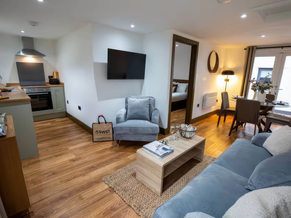 A living room with sofa and kitchen area at Beech Cottages Llanrwst