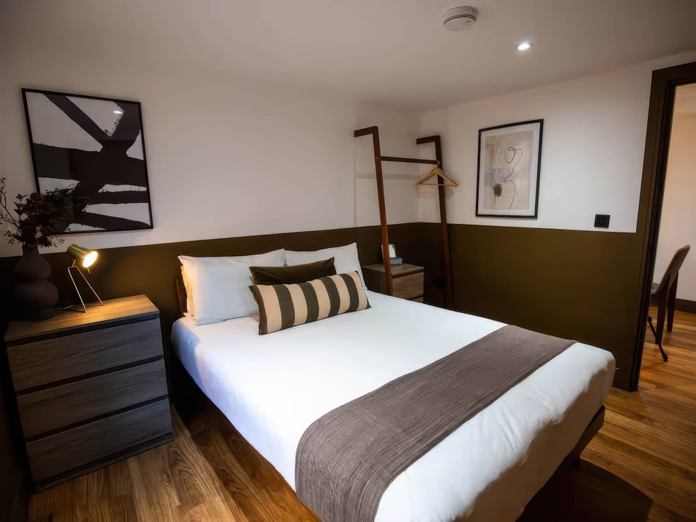 A bedroom with a bed, bedside table and artwork at Beech Cottages in Llanrwst