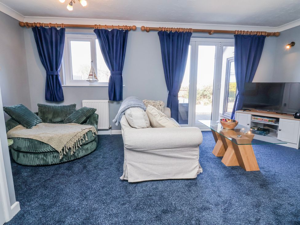 A living room with a couch, armchair and television at Sea Spray in Westward Ho!