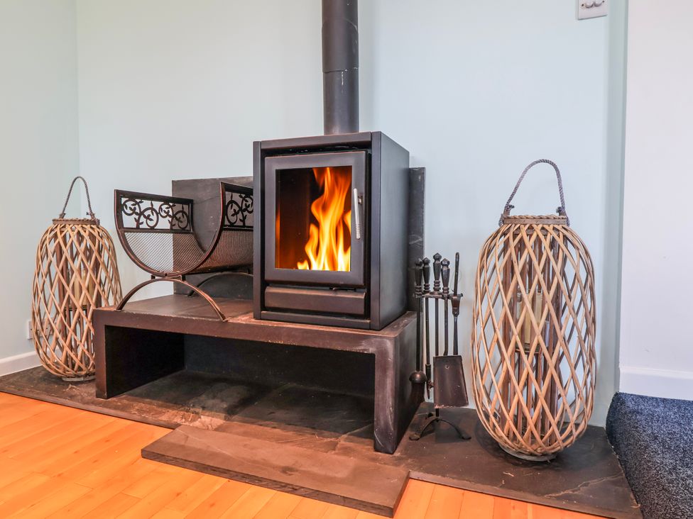 A fireplace with a wood stove and fire in Sea Spray Westward Ho!