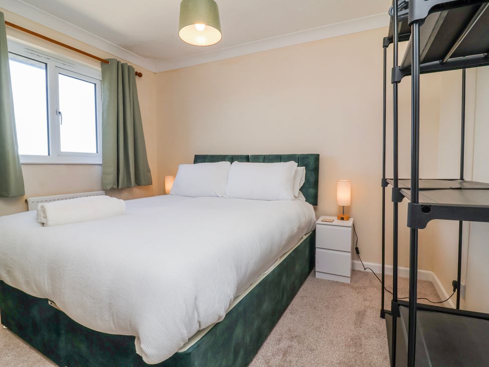 A bedroom with a bed and nightstand at Sea Spray in Westward Ho!