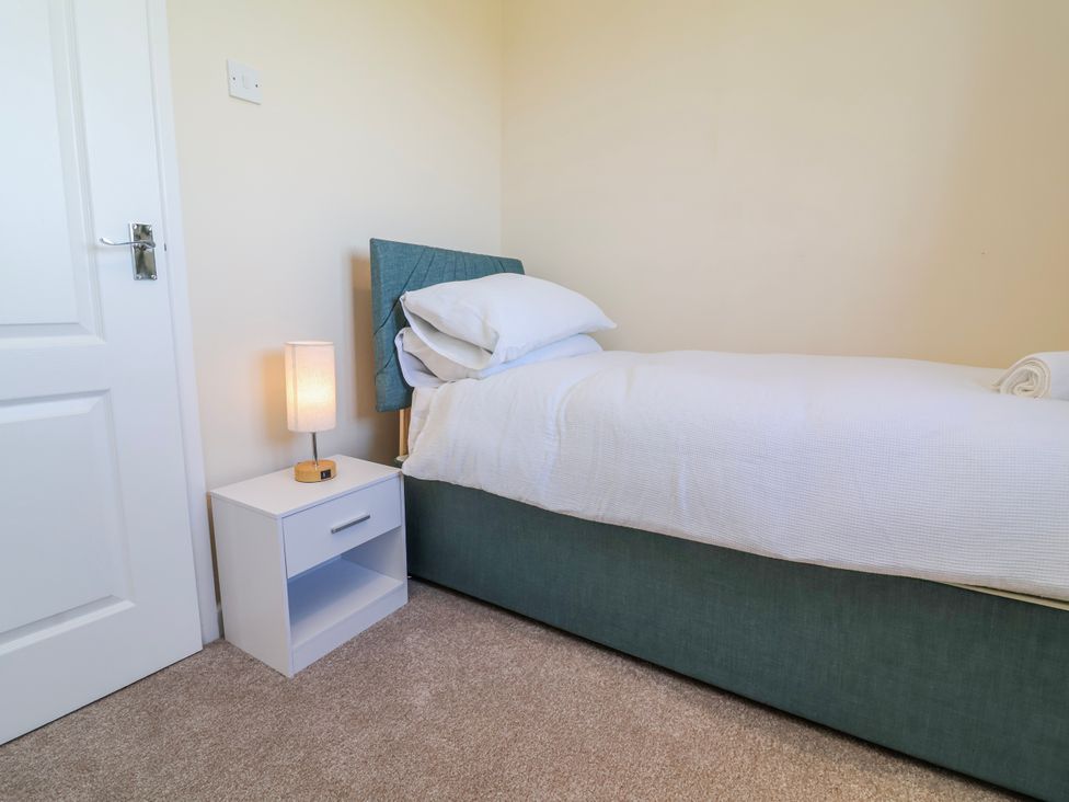 A bedroom with a bed and bedside table at Sea Spray in Westward Ho!