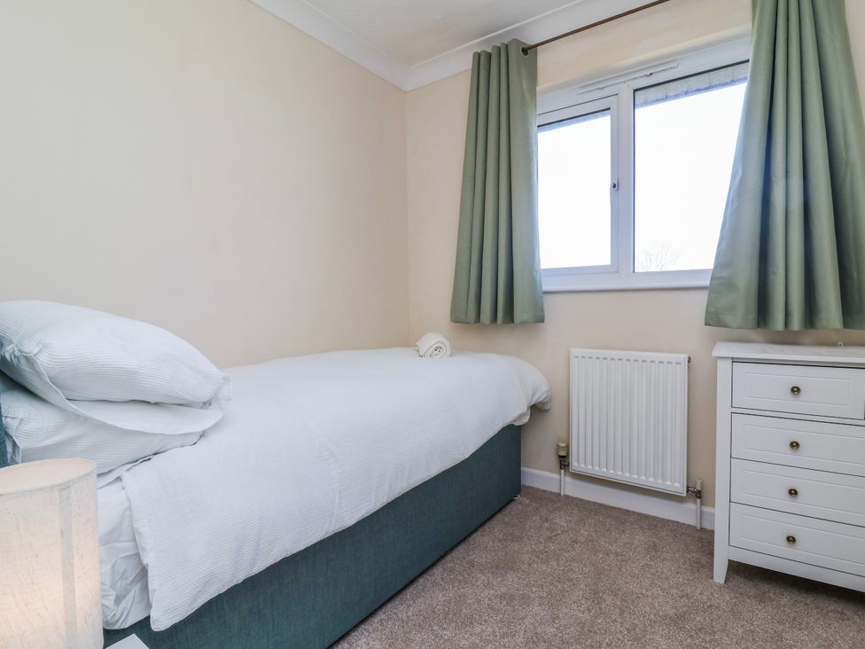 A bedroom with a bed and nightstand at Sea Spray in Westward Ho!