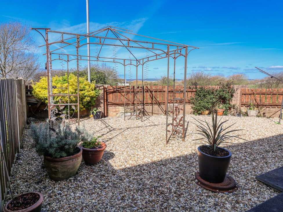 A garden with a metal gazebo and potted plants at Sea Spray in Westward Ho!