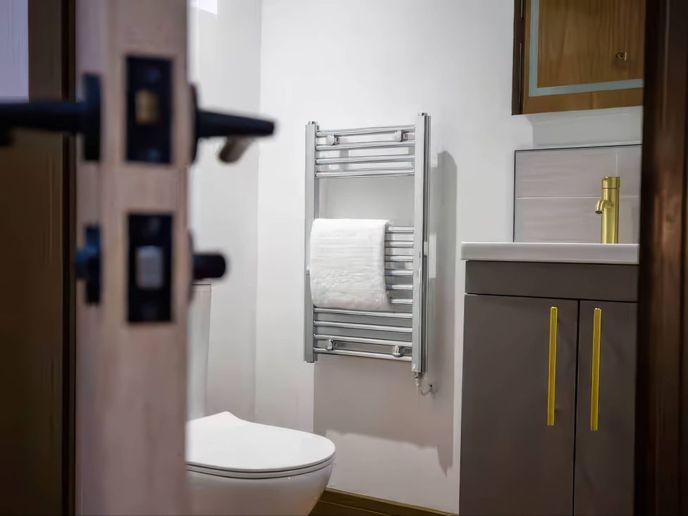 A bathroom featuring a toilet, sink, and towel radiator at Fir Cottages in Llanrwst