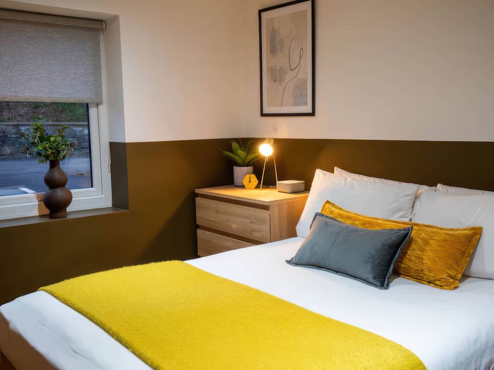 A bedroom with a bed and nightstand at Fir Cottages in Llanrwst