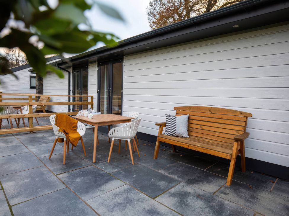 An outdoor patio with a wooden table and chairs at Silver Birch Cottage Llanrwst
