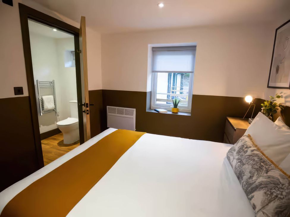 A bedroom with a bed and an adjoining bathroom at Silver Birch Cottage in Llanrwst
