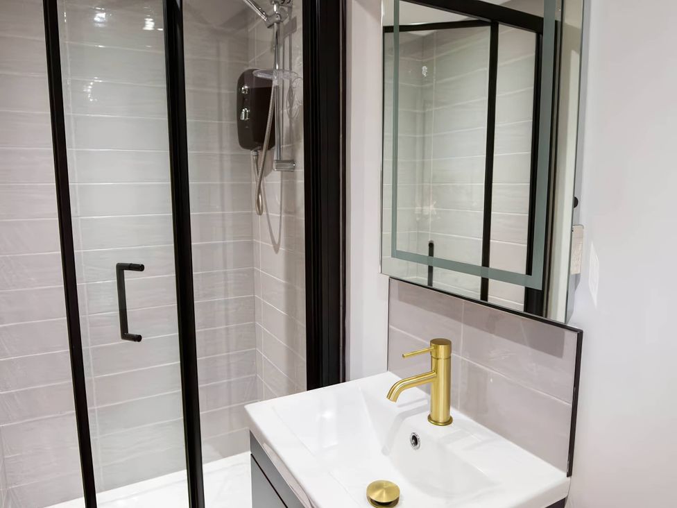 A bathroom with a shower enclosure and a sink at Silver Birch Cottage Llanrwst