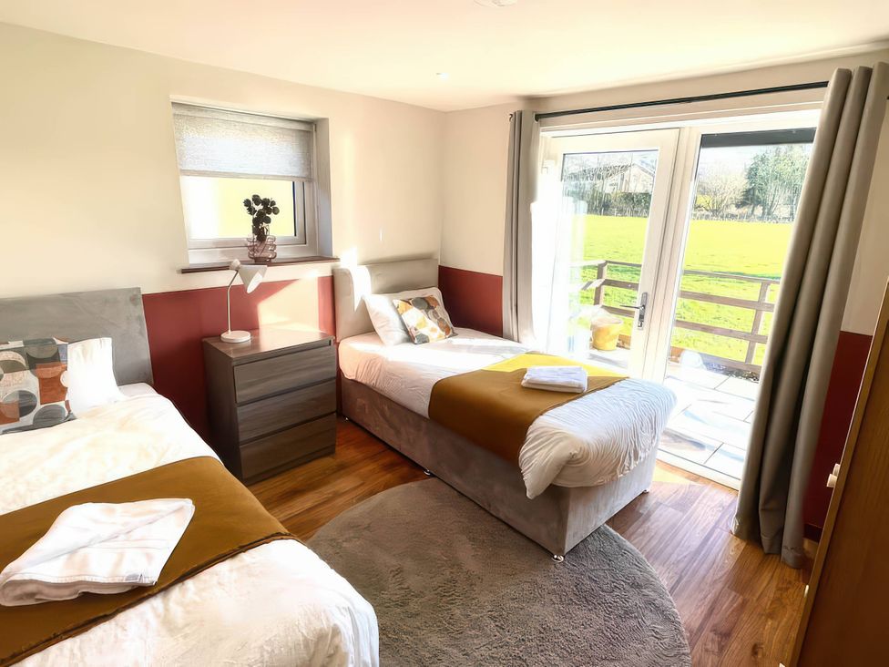 A bedroom with two beds and a door leading outside at River View Cottage Llanrwst