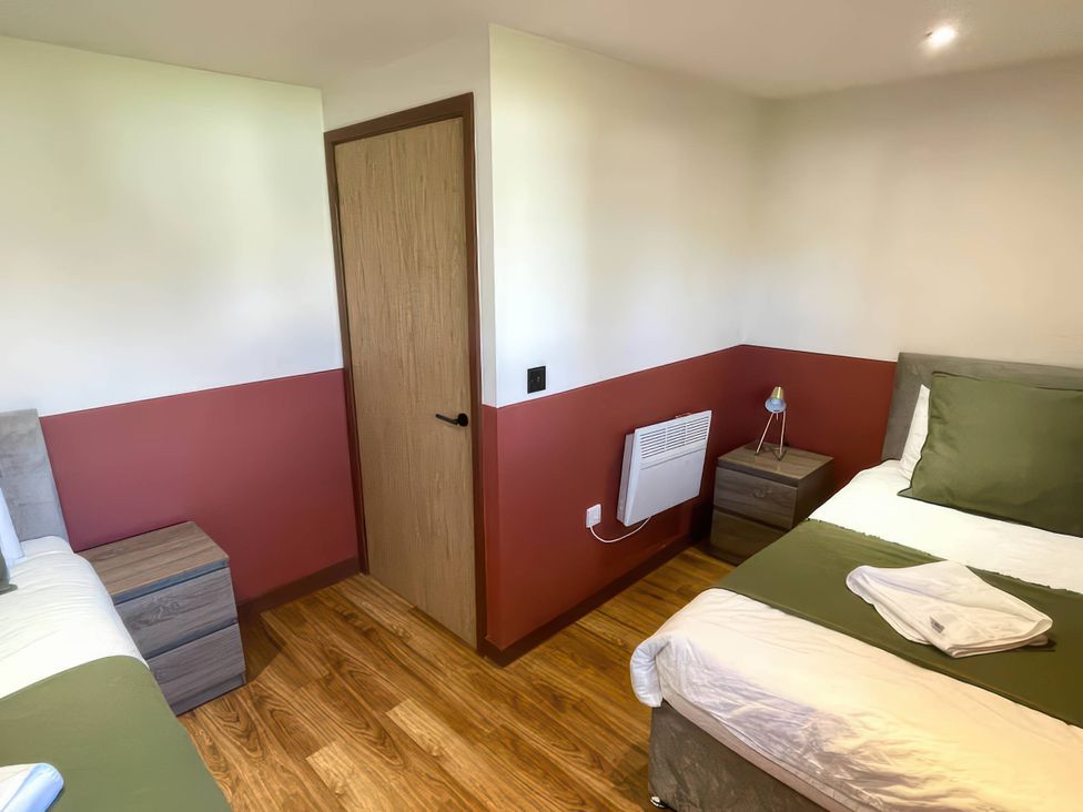 A bedroom with two beds and a nightstand at River View Cottage Llanrwst