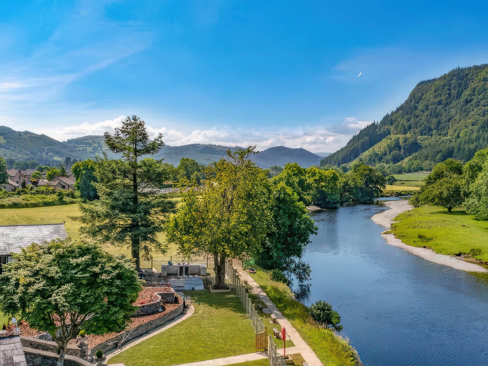 A view of a river with mountains and trees at Mountain View Cottage in Llanrwst