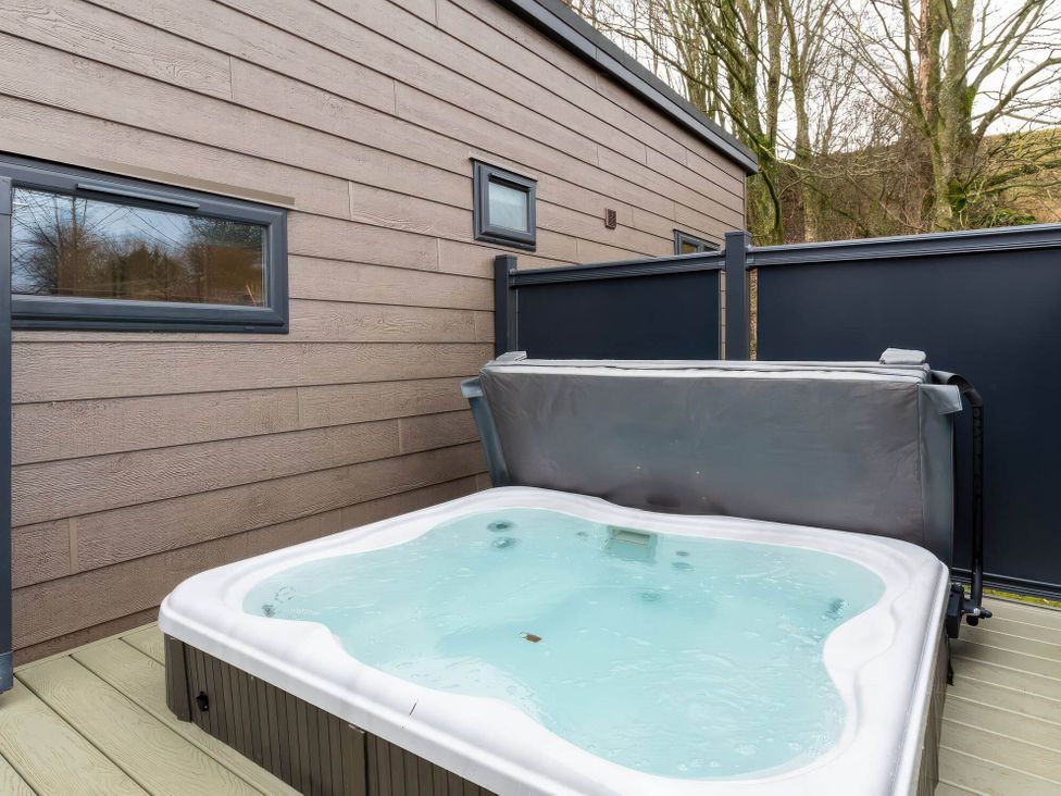A hot tub on a deck next to an exterior wall at The Falls in Leyburn