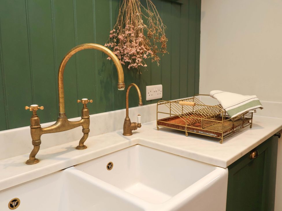 A kitchen sink with a golden faucet and a dish rack at Fairview in Darsham