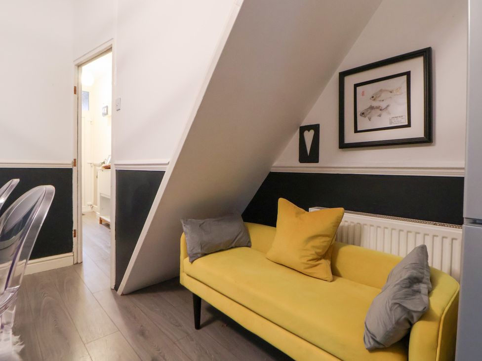 A living room with a yellow sofa and artwork at 50 Gladstone Avenue Chester