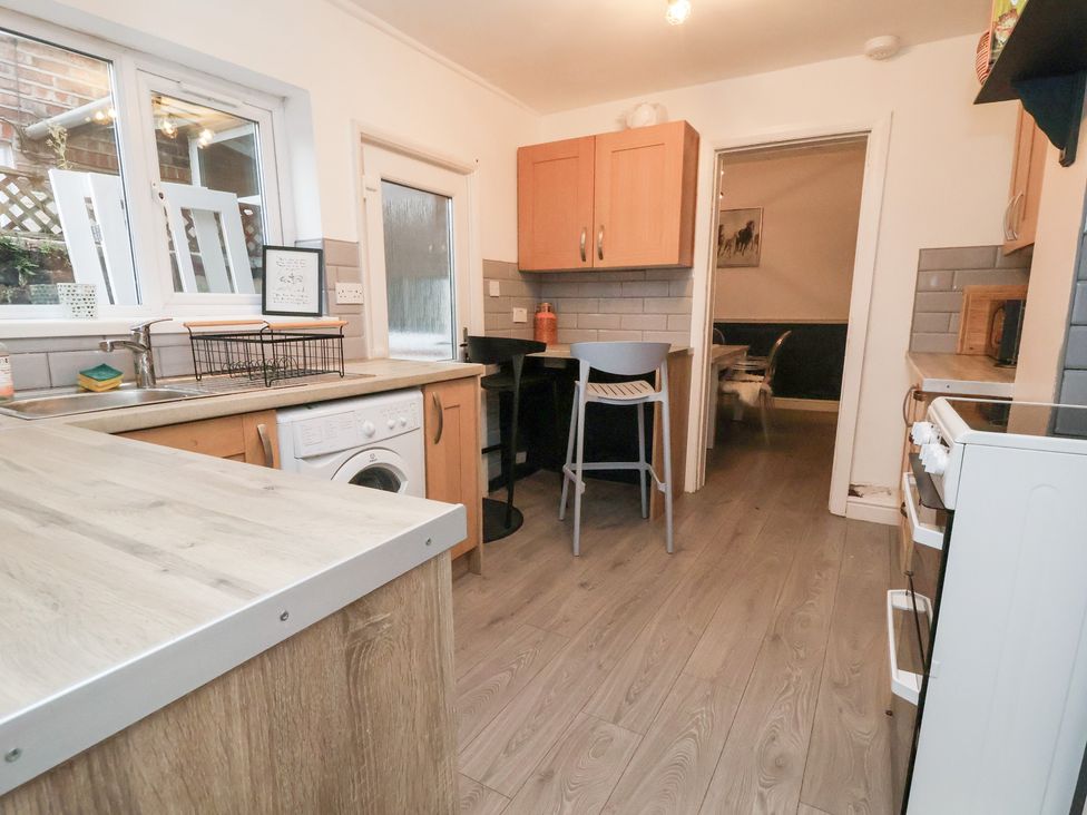 A kitchen with a washing machine and bar stools at 50 Gladstone Avenue in Chester