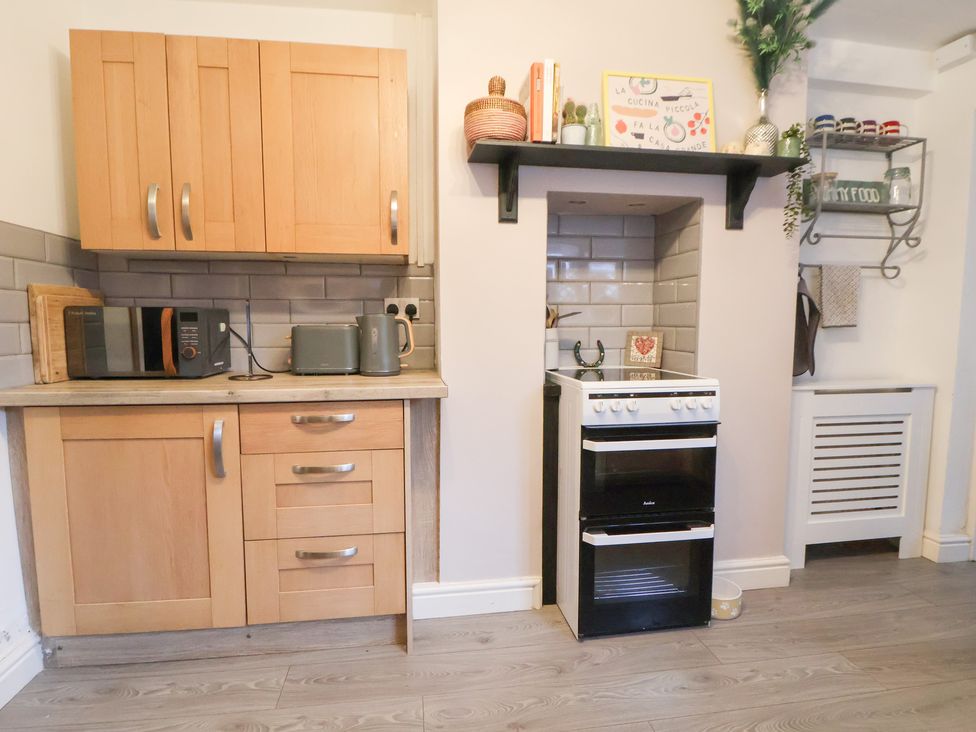 A kitchen with cabinets, microwave, kettle, cooker, and shelves at 50 Gladstone Avenue Chester