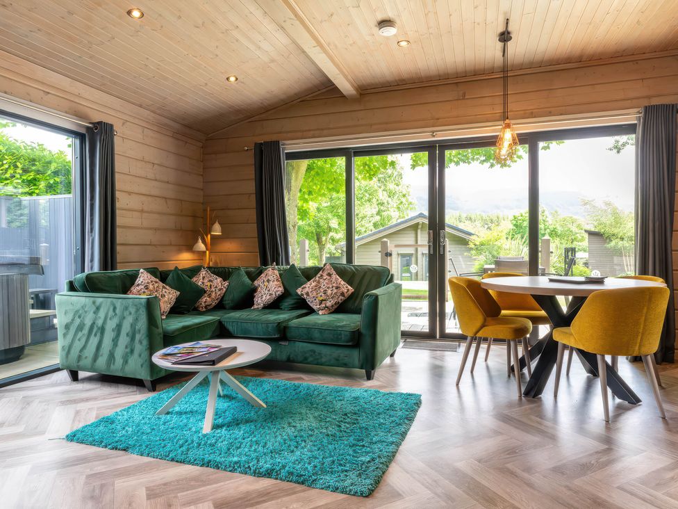 A living room with a green sofa and a dining area at Middleham (Pet) Leyburn