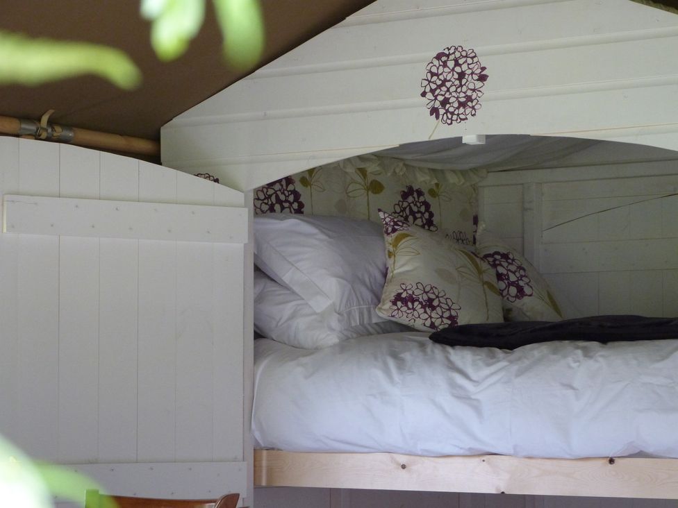 A sleeping area with a bed and cushions at Aeron Newcastle Emlyn