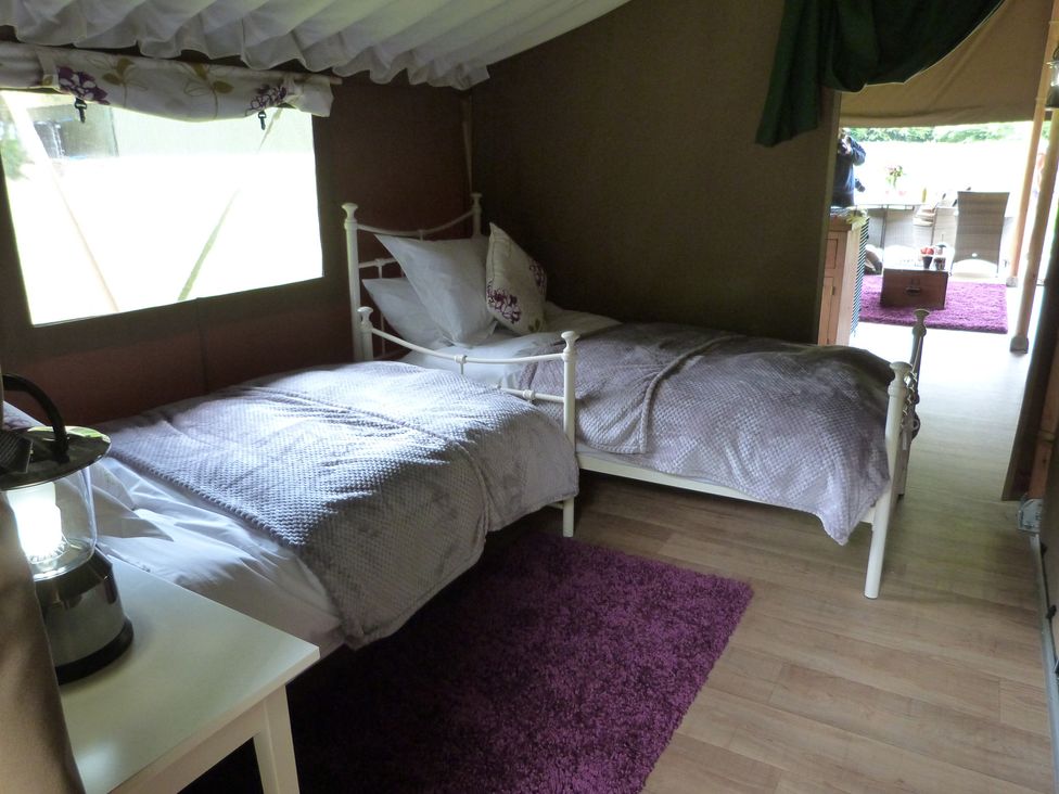 A bedroom with two beds and a lamp at Aeron in Newcastle Emlyn