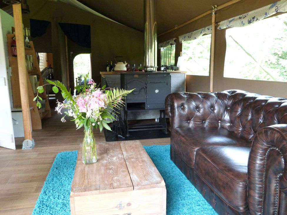A living room with a sofa, coffee table, and wood stove at Teifi in Newcastle Emlyn