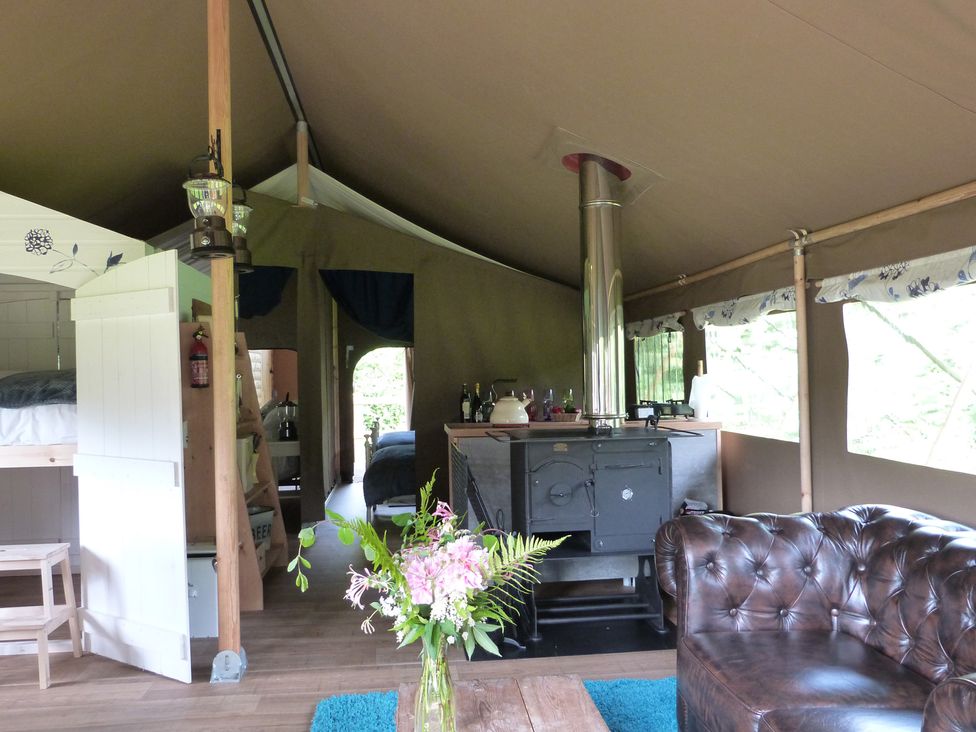A tent interior with a wood stove and sofa at Teifi Newcastle Emlyn