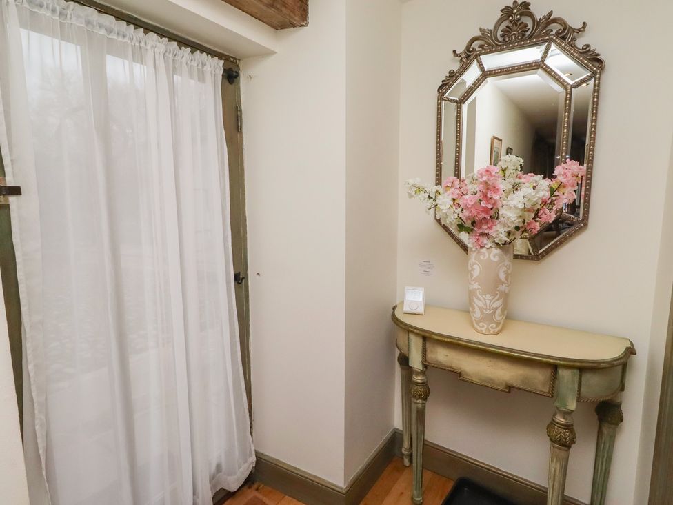 A vase with flowers and a mirror on the wall in a hallway at The French 