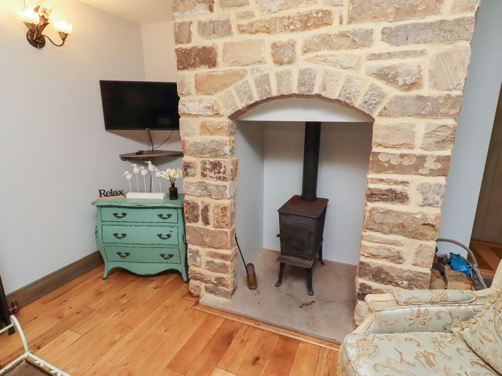 A living room with a stone fireplace and a green dresser at The French