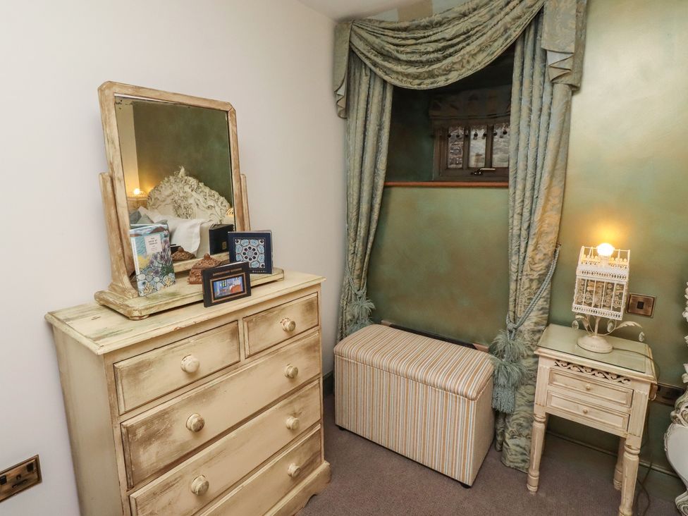 A bedroom with a dresser, mirror, and storage bench at The French 