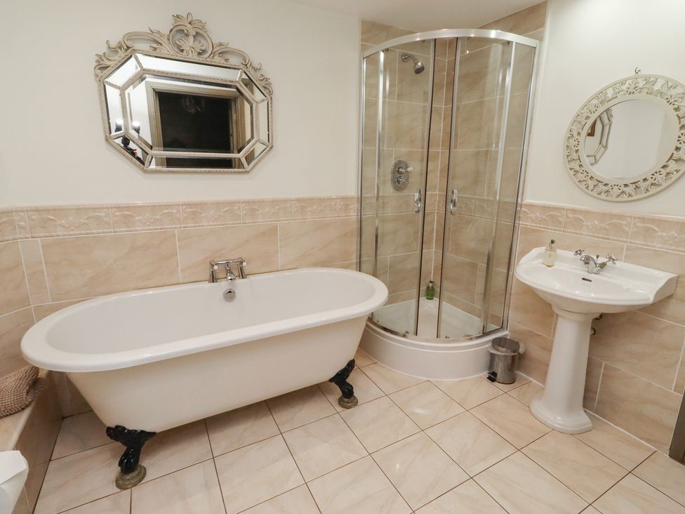 A bathroom with a bathtub, shower, sink, and mirror at The French
