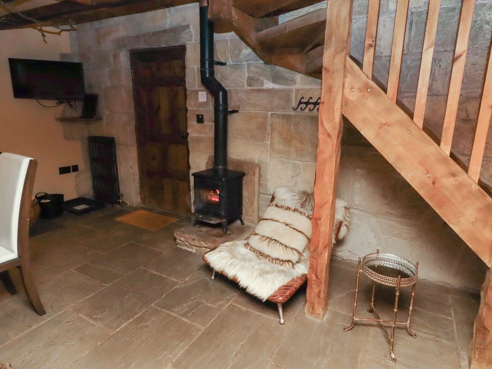 A sitting room with a stove and a chair at The Medieval Romantic in 