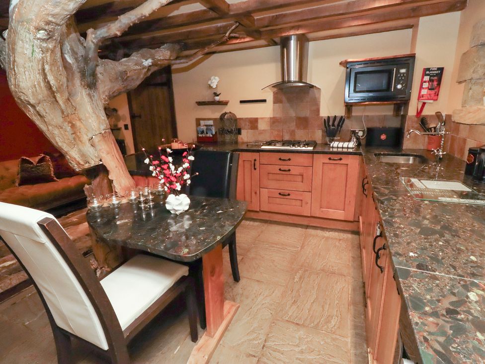 A kitchen with wooden cabinets and a dining table at The Medieval Romantic