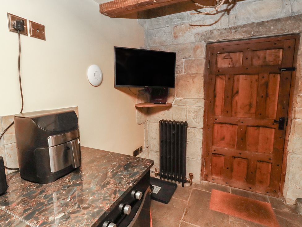 A kitchen with an air fryer, television, and wooden door at The Medieval Romantic