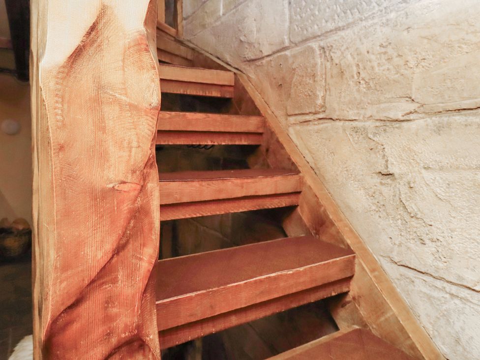 A wooden staircase with a stone wall at The Medieval Romantic