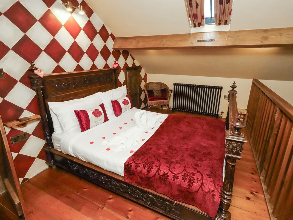 A bedroom with a wooden bed and decorative wall at The Medieval Romantic in 