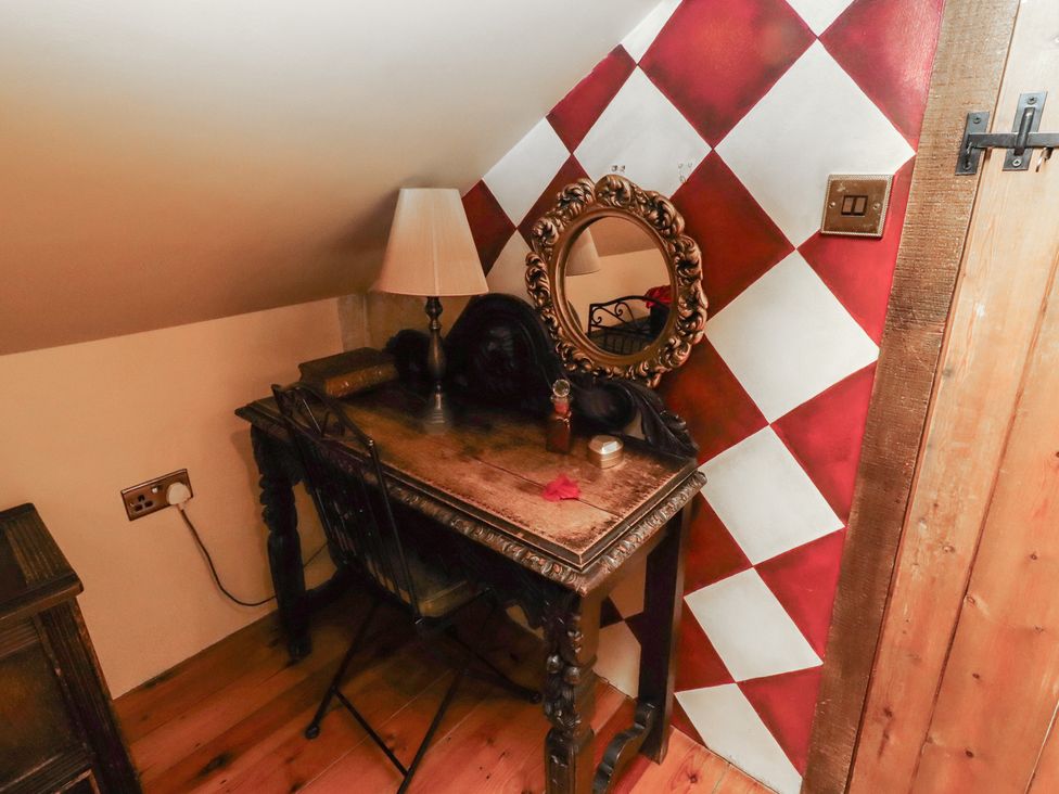 A desk with a lamp and a mirror in the attic at The Medieval Romantic