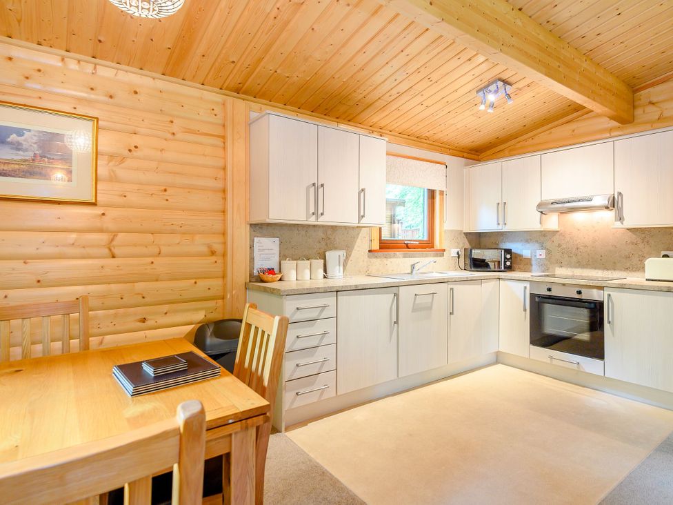 A kitchen with cabinets and a table at Maple Lodge in Louth