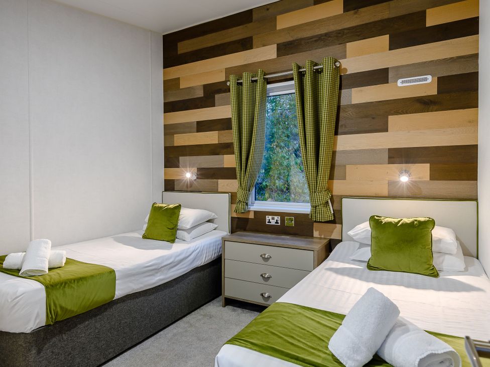 A bedroom with twin beds and a nightstand at Anderby Spa (Pet) Louth