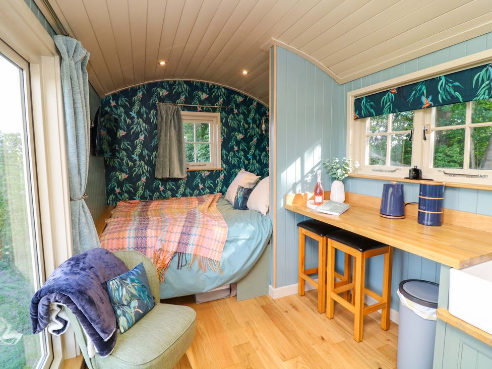 A tiny house with a bed and table at Kingfisher Hut