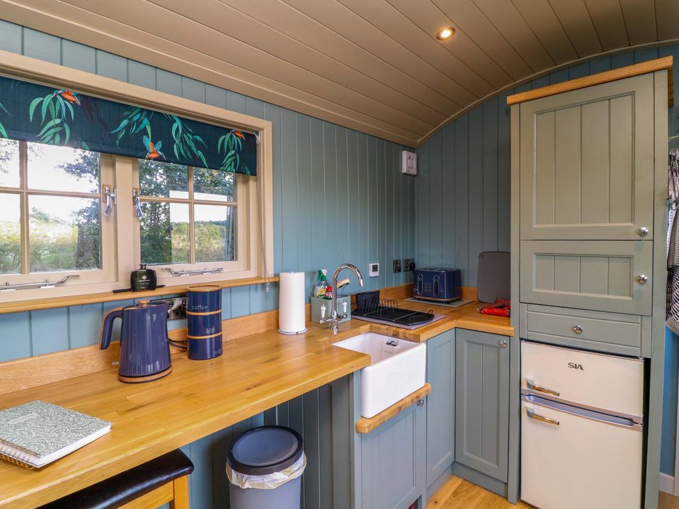 A kitchen with sink, kettle, and countertop at Kingfisher Hut