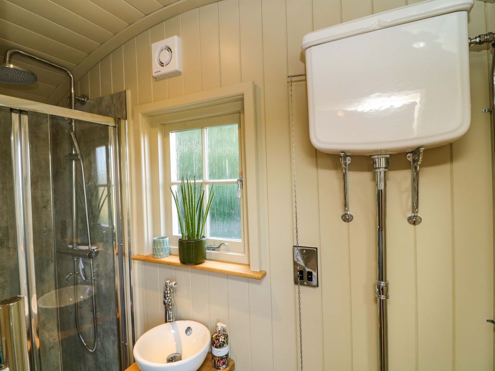 A bathroom with a shower, toilet, and sink at Kingfisher Hut