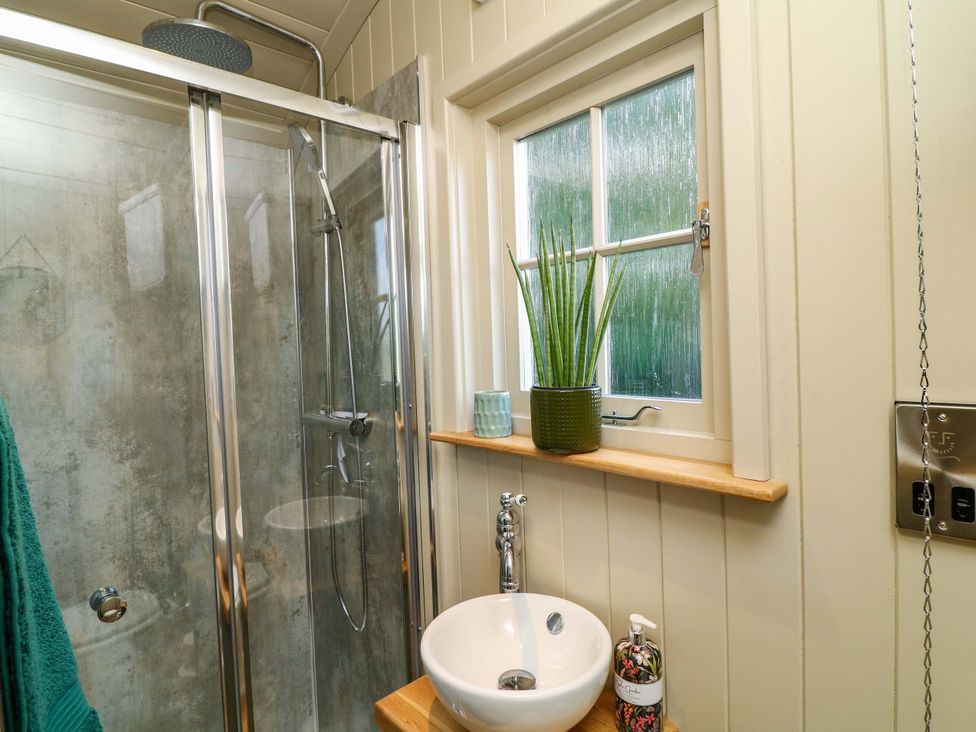A bathroom with a shower and sink at Kingfisher Hut