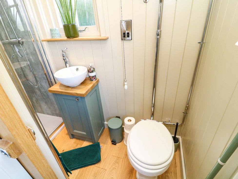 A bathroom with a shower, toilet, and sink at Kingfisher Hut