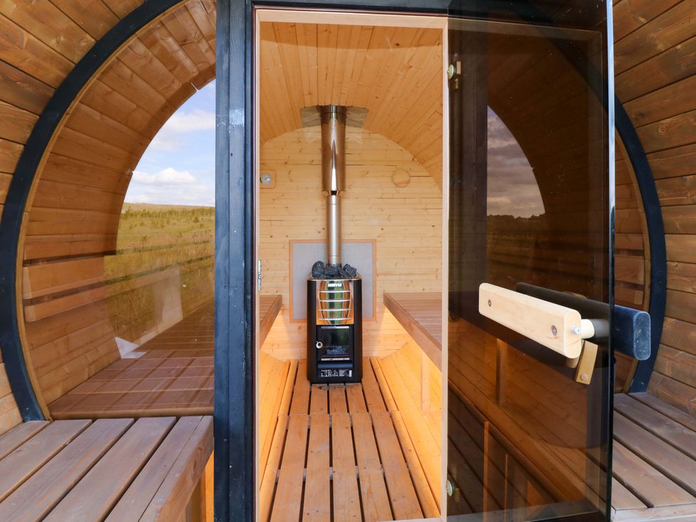 A sauna with wooden benches and a wood stove at Kingfisher Hut