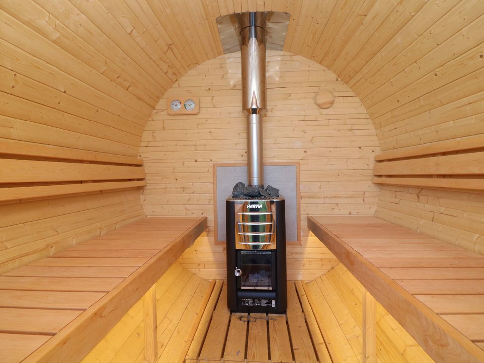 A sauna with wooden benches and a stove at Kingfisher Hut