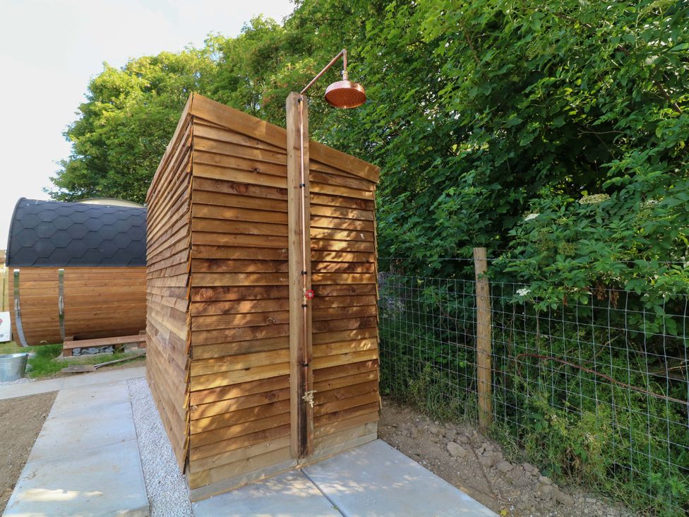 An outdoor shower made of wood in a garden setting at Kingfisher Hut